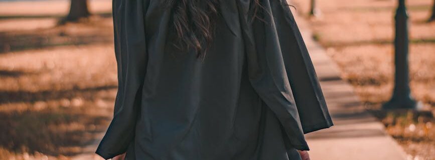 woman in black long sleeve dress standing on brown concrete pathway